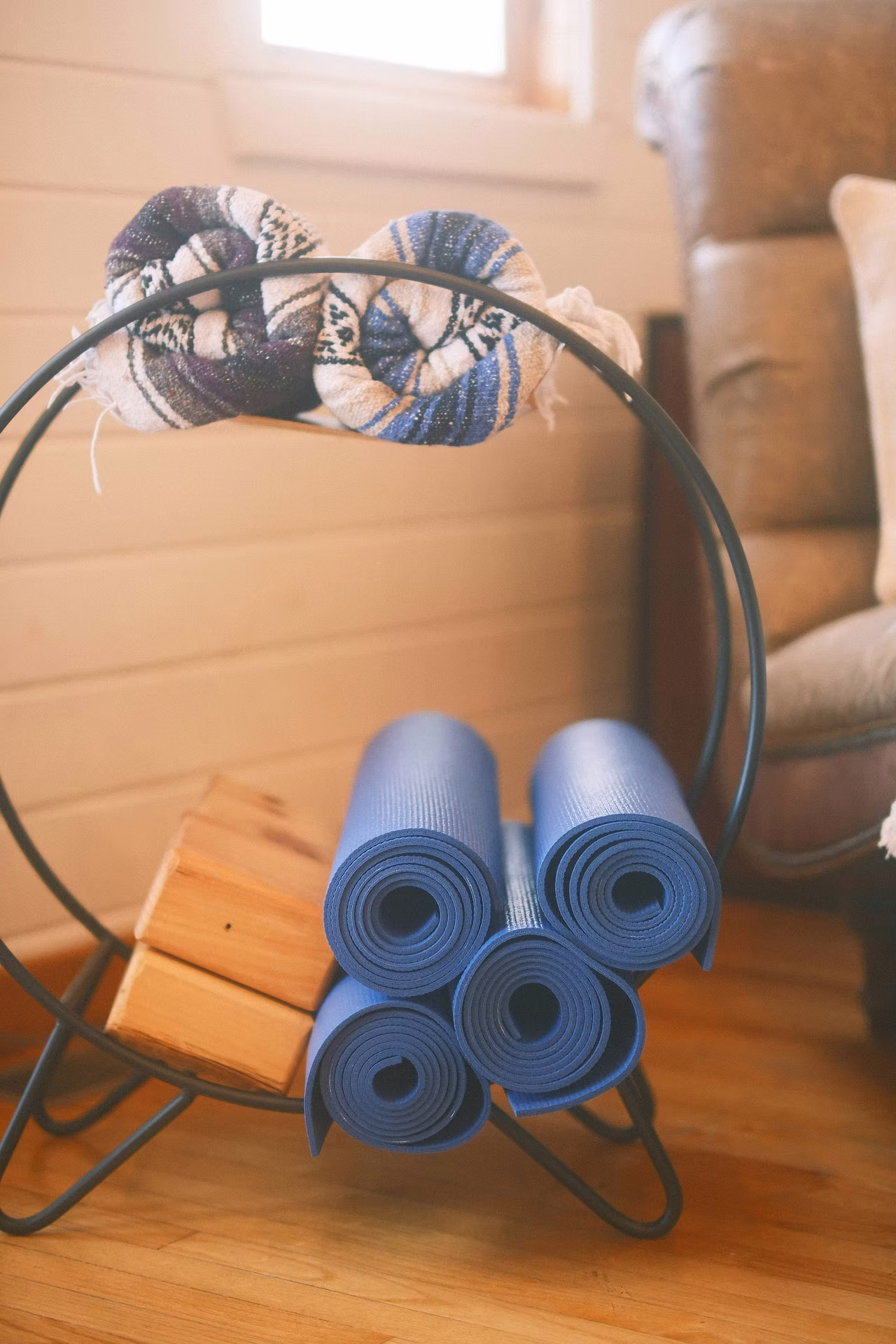 Quatre tapis bleus roulés dans un rangement métallique, avec des briques en bois et des textiles.